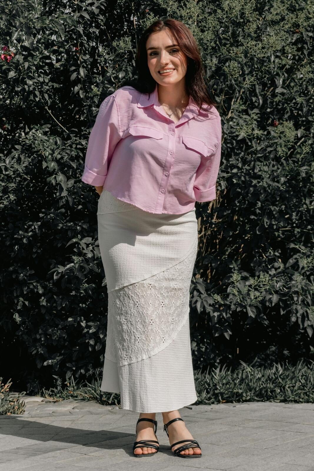 Jupe longue en dentelle écrue portée avec une chemise rose